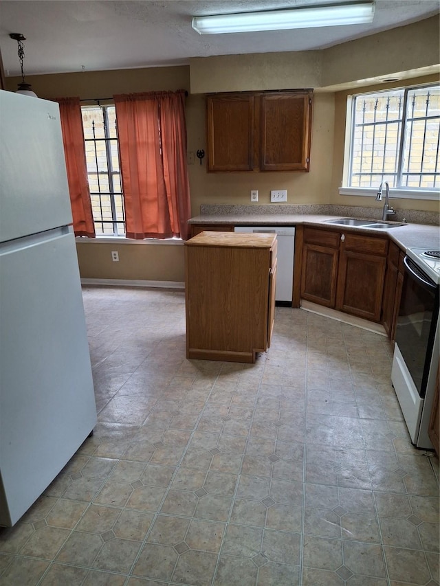 kitchen featuring a kitchen island, light countertops, a sink, and white appliances