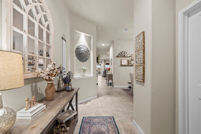 hall with baseboards and visible vents