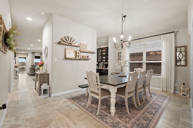 dining area featuring a healthy amount of sunlight, baseboards, and an inviting chandelier