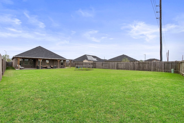 view of yard with a trampoline, a fenced backyard, and a gazebo