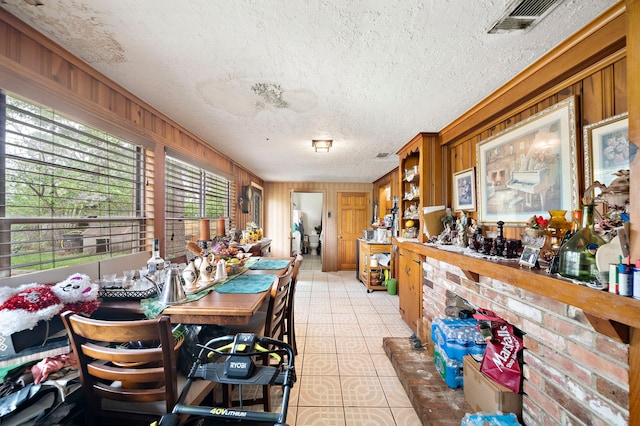 dining space featuring wooden walls, a textured ceiling, and visible vents