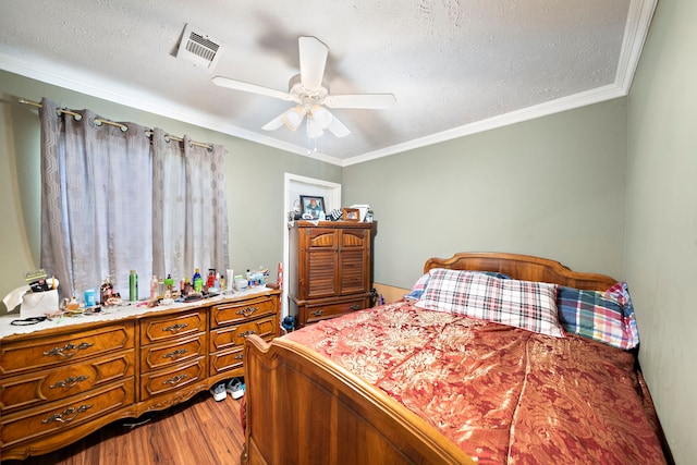bedroom featuring visible vents, wood finished floors, a ceiling fan, and ornamental molding