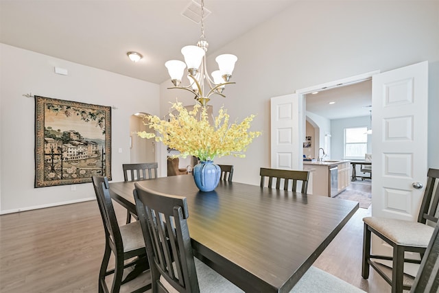 13710 Alaskan Brown Bear Trl, Crosby, TX 77532 - dining space with lofted ceiling, light wood finished floors, a notable chandelier, and arched walkways