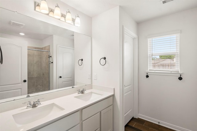 bathroom featuring baseboards, a tile shower, wood finished floors, and a sink