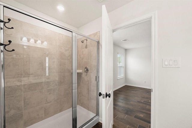 full bath featuring a shower stall, baseboards, and wood finish floors