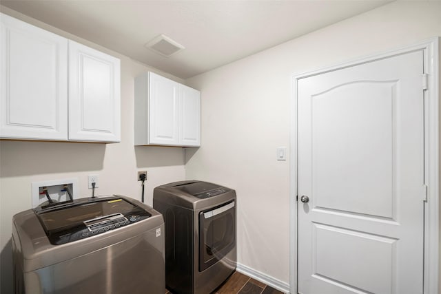 clothes washing area featuring baseboards, dark wood finished floors, washing machine and clothes dryer, visible vents, and cabinet space