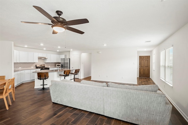 living area with dark wood-type flooring, baseboards, visible vents, ceiling fan, and recessed lighting