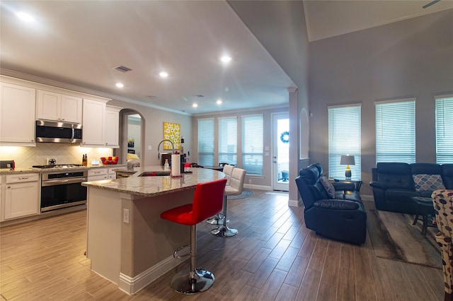 1627 Carriage Oaks Ln, Katy, TX 77494 - kitchen with visible vents, arched walkways, a sink, open floor plan, and appliances with stainless steel finishes