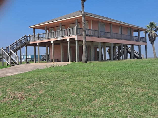 exterior space with stairs, driveway, a shingled roof, and a yard