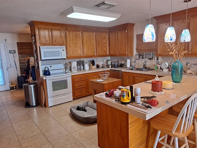kitchen with white appliances, visible vents, brown cabinets, and a sink