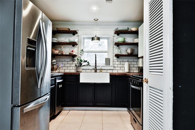 kitchen with a sink, open shelves, dark cabinets, and appliances with stainless steel finishes