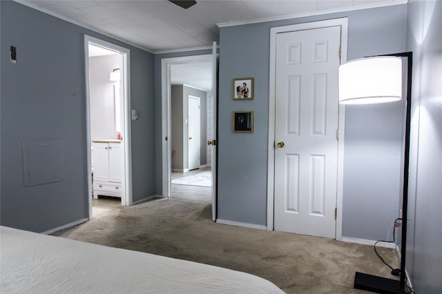 carpeted bedroom featuring ensuite bathroom, baseboards, and ornamental molding