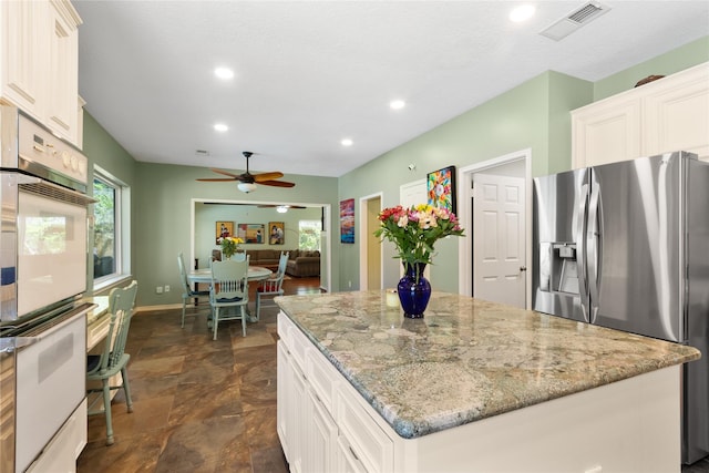 12510 Beauline Abbey St, Tomball, TX 77377 - kitchen featuring stainless steel fridge, a ceiling fan, white double oven, a kitchen island, and light stone counters