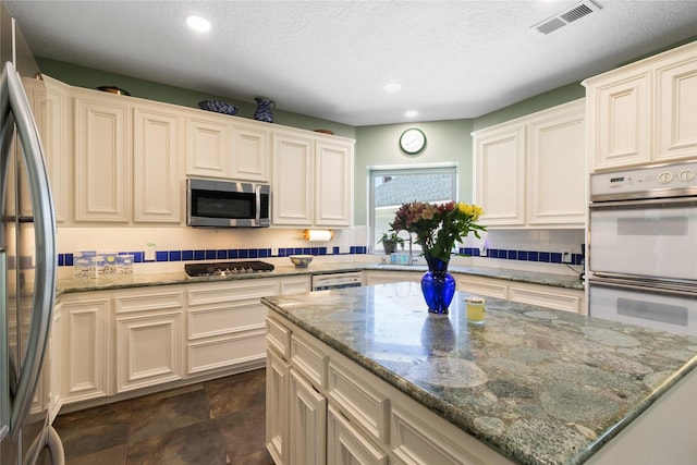 12510 Beauline Abbey St, Tomball, TX 77377 - kitchen with stone counters, visible vents, appliances with stainless steel finishes, a kitchen island, and recessed lighting