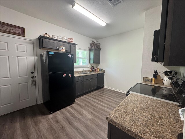 208 County Road 308, Cleveland, TX 77327 - kitchen featuring a sink, wood finished floors, a textured ceiling, visible vents, and black appliances