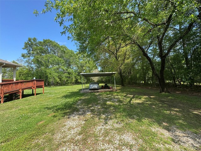 208 County Road 308, Cleveland, TX 77327 - view of yard featuring a detached carport, a wooden deck, and driveway