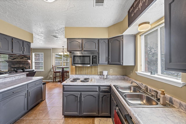 3102 Blue Hills Dr, Missouri City, TX 77459 - kitchen featuring light countertops, stainless steel microwave, white electric cooktop, a sink, and visible vents