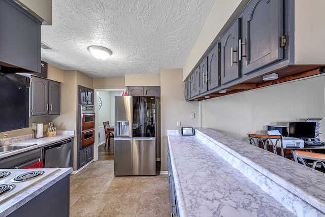 3102 Blue Hills Dr, Missouri City, TX 77459 - kitchen with light countertops, a sink, appliances with stainless steel finishes, a textured ceiling, and gray cabinetry