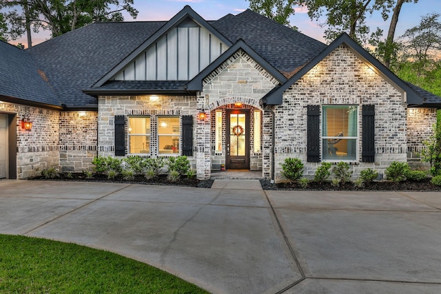 2711 Constantine St, New Caney, TX 77357 - view of front of property with board and batten siding, a shingled roof, brick siding, and stone siding
