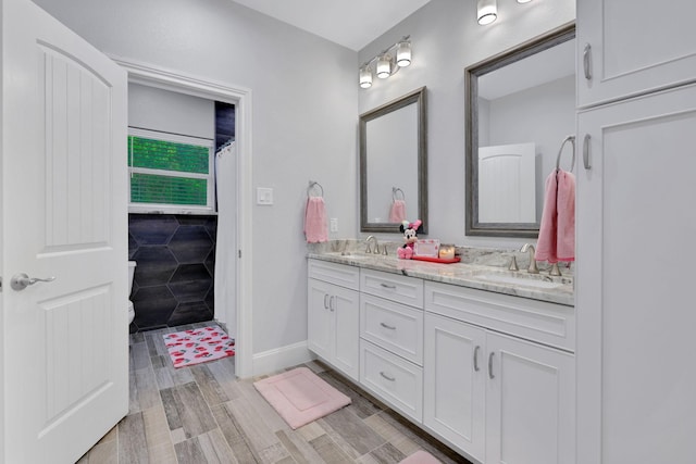 2711 Constantine St, New Caney, TX 77357 - full bath with double vanity, wood finished floors, and baseboards