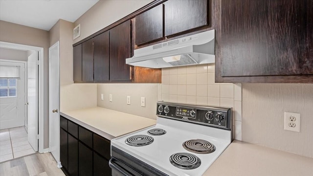 1302 20th St, Huntsville, TX 77340 - kitchen with electric stove, under cabinet range hood, light countertops, decorative backsplash, and dark brown cabinetry