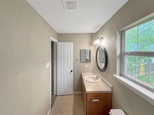 bathroom featuring tile patterned flooring, vanity, baseboards, a textured ceiling, and visible vents