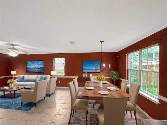 dining space featuring light tile patterned floors, ceiling fan with notable chandelier, baseboards, and visible vents