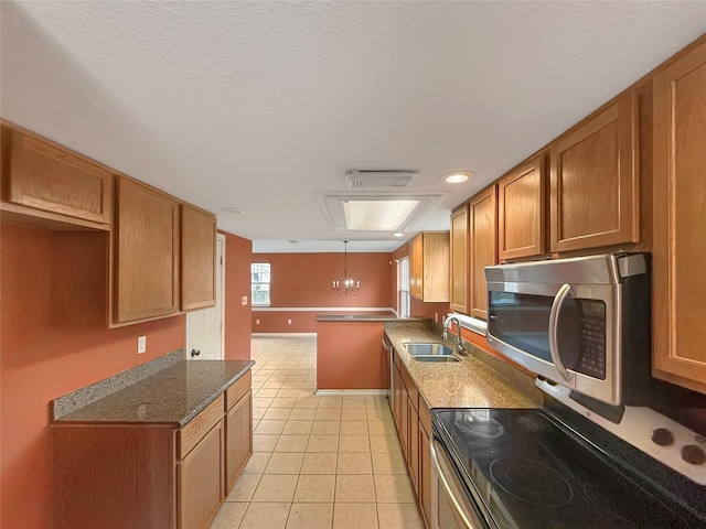 kitchen with light tile patterned flooring, a sink, pendant lighting, appliances with stainless steel finishes, and brown cabinets