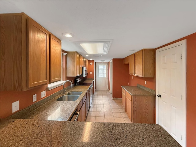 kitchen featuring light tile patterned flooring, a sink, brown cabinetry, and appliances with stainless steel finishes