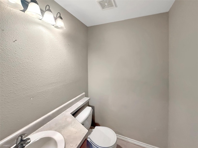 bathroom featuring a textured wall, visible vents, toilet, and vanity