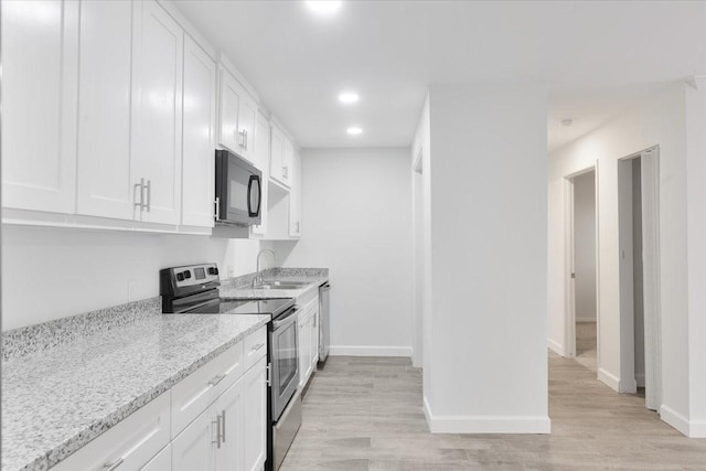 9566 Windswept Ln Unit 9566, Houston, TX 77063 - kitchen with stainless steel range with electric stovetop, black microwave, white cabinets, light stone counters, and recessed lighting