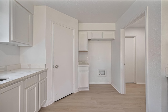 6219 Canada Dr, Pasadena, TX 77505 - kitchen featuring light wood-type flooring, light stone counters, and white cabinetry