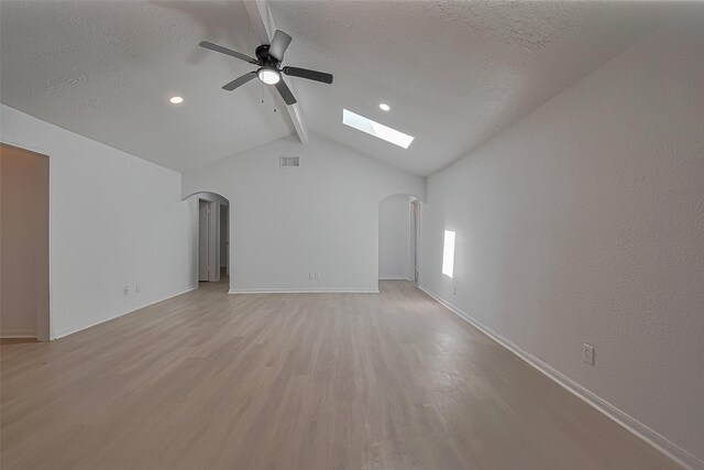 6219 Canada Dr, Pasadena, TX 77505 - unfurnished living room with light wood-style floors, arched walkways, lofted ceiling with skylight, and a ceiling fan