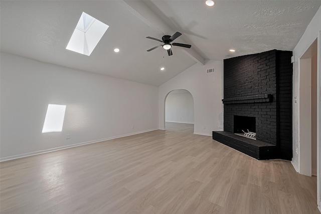 6219 Canada Dr, Pasadena, TX 77505 - unfurnished living room featuring baseboards, a textured ceiling, light wood-style floors, vaulted ceiling with skylight, and a ceiling fan