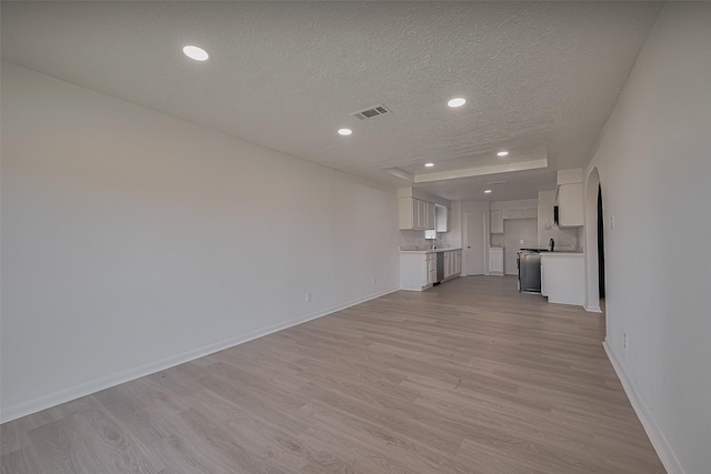 6219 Canada Dr, Pasadena, TX 77505 - unfurnished living room featuring a textured ceiling, baseboards, recessed lighting, arched walkways, and light wood-style floors