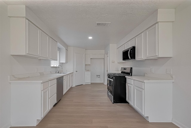 6219 Canada Dr, Pasadena, TX 77505 - kitchen featuring white cabinetry, stainless steel appliances, a sink, light wood-style floors, and visible vents