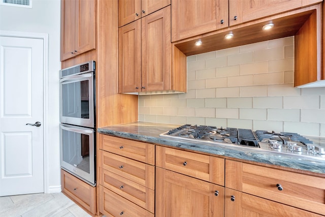kitchen featuring visible vents, stone countertops, stainless steel appliances, and decorative backsplash