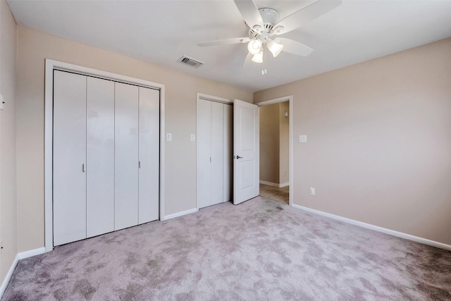 unfurnished bedroom with ceiling fan, visible vents, carpet, baseboards, and multiple closets