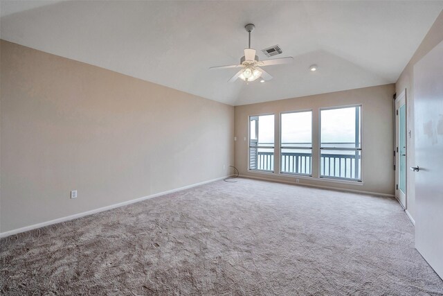 carpeted empty room featuring visible vents, ceiling fan, vaulted ceiling, and baseboards