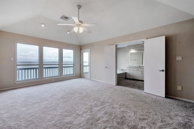 unfurnished bedroom featuring lofted ceiling, visible vents, baseboards, carpet, and ensuite bath