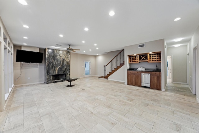 301 Isles End Rd, Tiki Island, TX 77554 - unfurnished living room featuring bar with sink, a high end fireplace, stairs, a ceiling fan, and recessed lighting