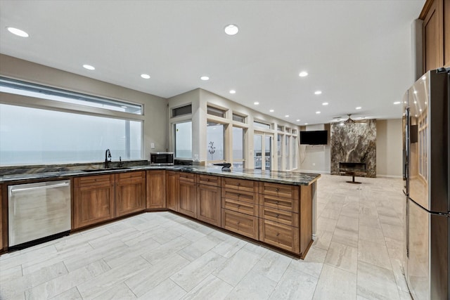 301 Isles End Rd, Tiki Island, TX 77554 - kitchen featuring stainless steel appliances, a sink, brown cabinets, dark stone counters, and recessed lighting