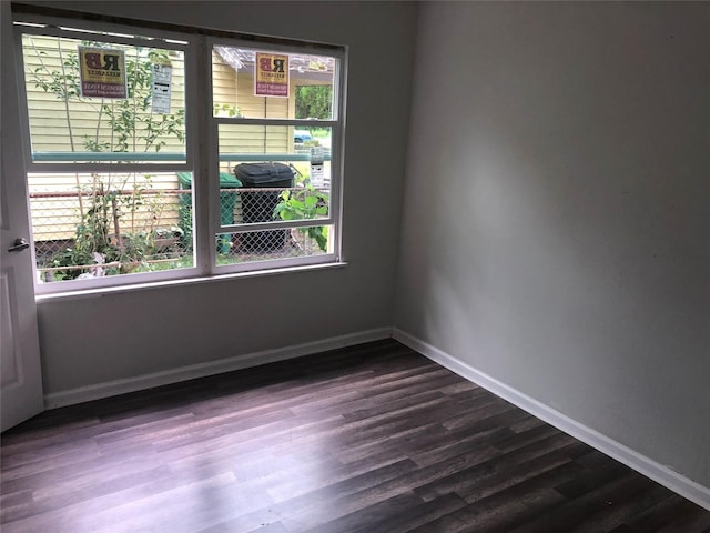 spare room featuring baseboards and dark wood-style floors