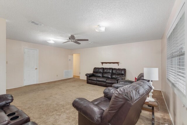carpeted living area with a textured ceiling, visible vents, and a ceiling fan