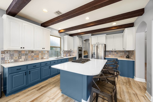 kitchen with blue cabinets, visible vents, arched walkways, a sink, and stainless steel appliances