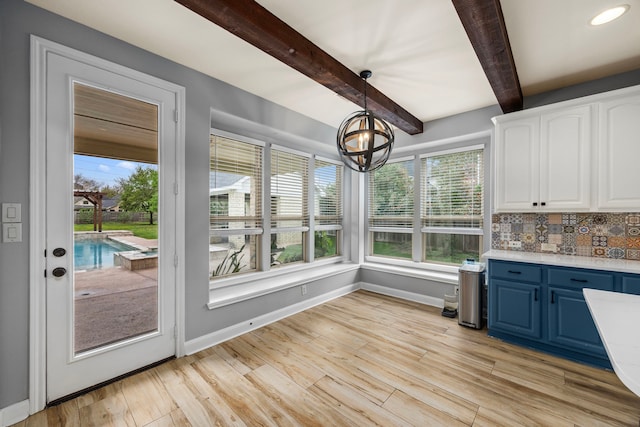 unfurnished sunroom featuring beam ceiling, a notable chandelier, and a wealth of natural light