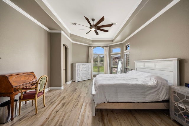 bedroom with visible vents, crown molding, baseboards, a tray ceiling, and light wood-style flooring