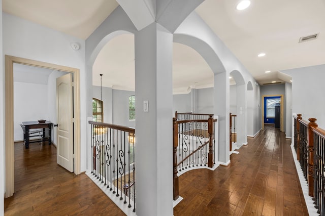 hallway with baseboards, visible vents, hardwood / wood-style flooring, and an upstairs landing