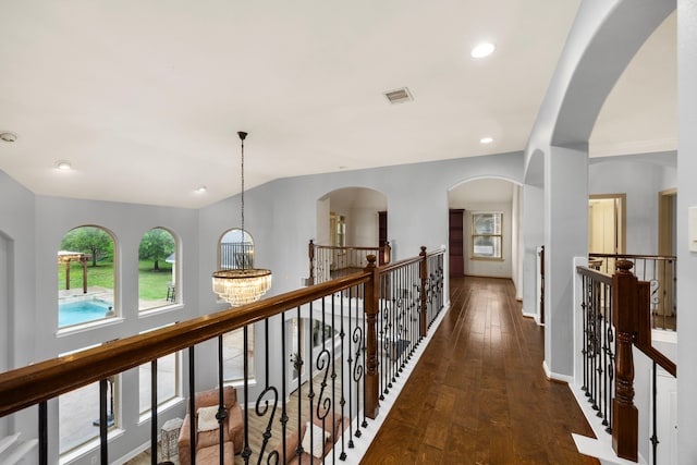 hallway featuring visible vents, dark wood-type flooring, plenty of natural light, and an upstairs landing