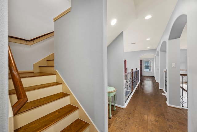 staircase featuring arched walkways, baseboards, recessed lighting, and hardwood / wood-style flooring